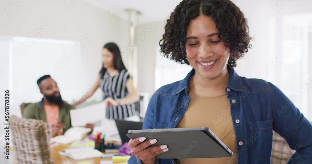 Happy biracial woman using tablet, working with diverse male and female friend, in slow motion Happy biracial woman using tablet, working with diverse male and female friend, in slow motion
