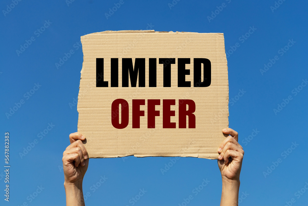 Limited offer text on cardboard held by 2 hands with isolated blue sky background. This message can be used for business concept about marketing campaign to convince customer to buy. Limited offer text on cardboard held by 2 hands with isolated blue sky background. This message can be used for business concept about marketing campaign to convince customer to buy.