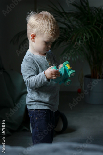 little boy playing with toy car in living room, dark background 
