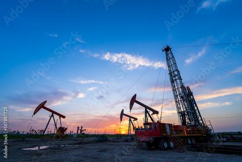 in the evening, oil pumps are running, The oil pump and the beautiful sunset reflected in the water, the silhouette of the beam pumping unit in the evening.