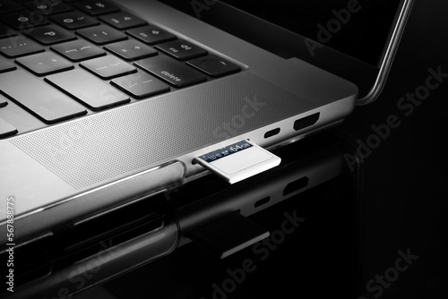 Close up view of a memory card inserted into a card reading slot of a laptop computer.