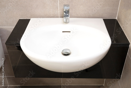 White modern washbasin on black granit counter