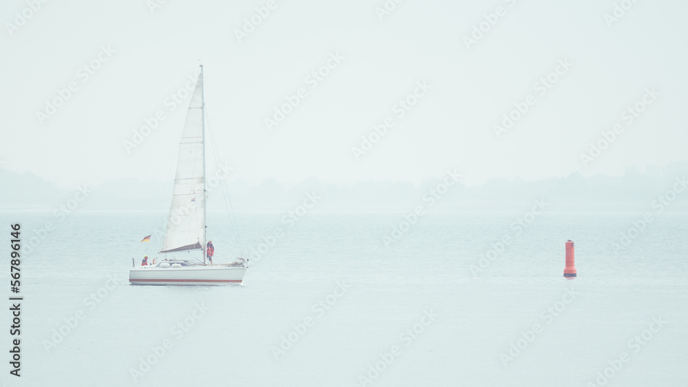 White sailing yacht in foggy mist North Sea in Netherlands