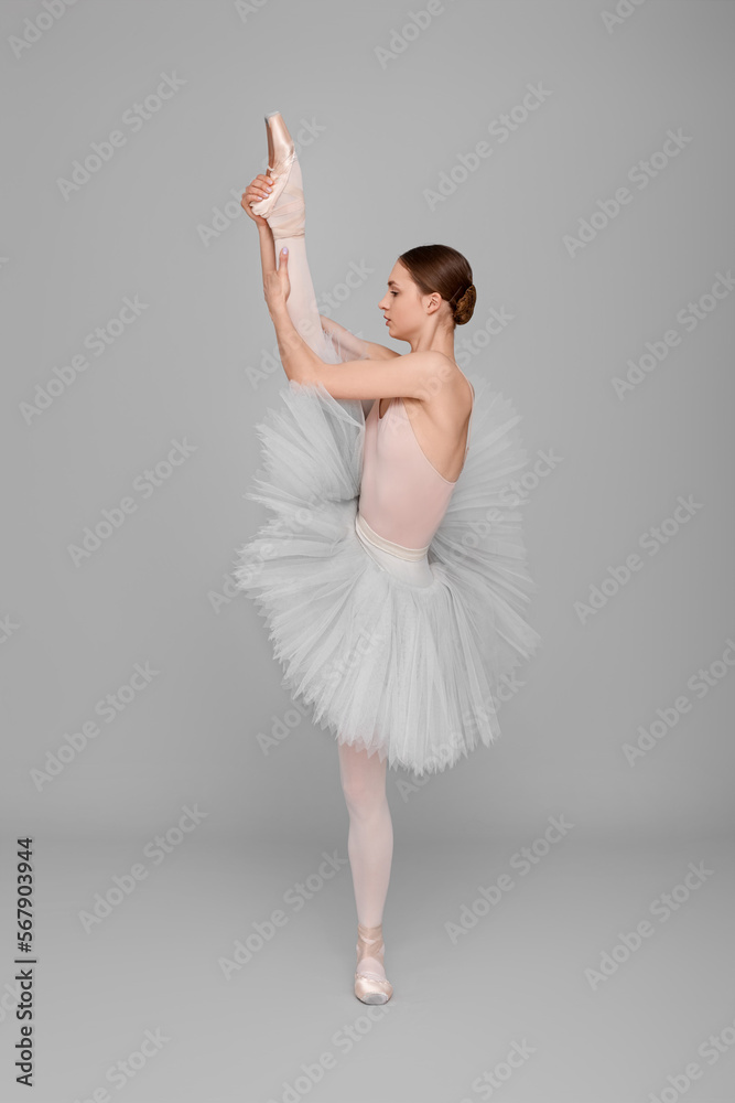 Naklejka premium Young ballerina practicing dance moves on light grey background