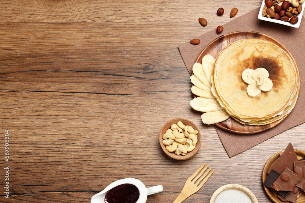 Delicious crepes with different products on wooden table, flat lay. Space for text