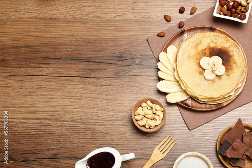 Delicious crepes with different products on wooden table, flat lay. Space for text