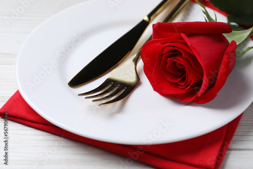 Beautiful place setting with dishware and rose for romantic dinner on white wooden table, closeup