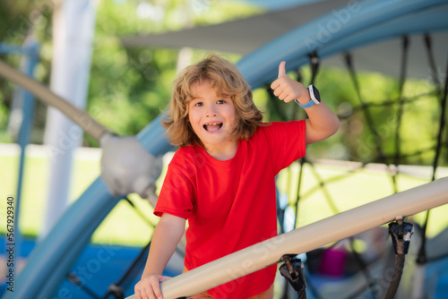 Child playing on playground. Kid play on school or kindergarten yard. Healthy summer activity for children. Little boy climbing playground.