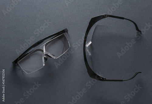 Two pairs of safety goggles on a dark gray background