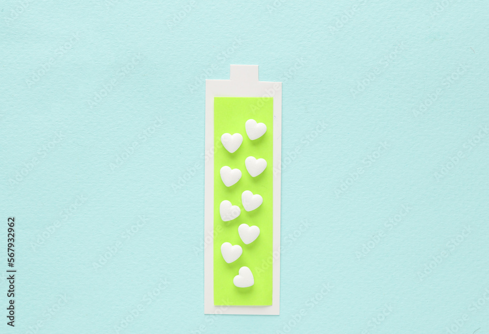Healthy heart concept. Paper cut full battery level with heart shaped pills on blue background Healthy heart concept. Paper cut full battery level with heart shaped pills on blue background