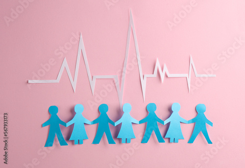 People Chain with a cardiological heart rhythm cut out of paper on pink background. Nation health photo