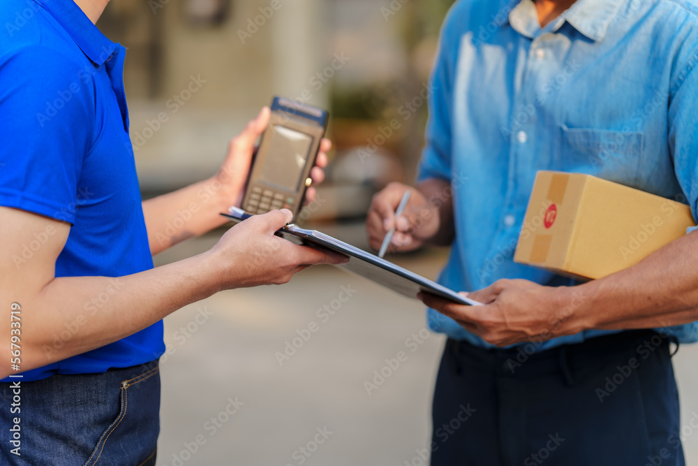 Delivery man asia people checking portable delivery device with parcel box to customer home address. give delivery box to customer and sign a signature of receiver people