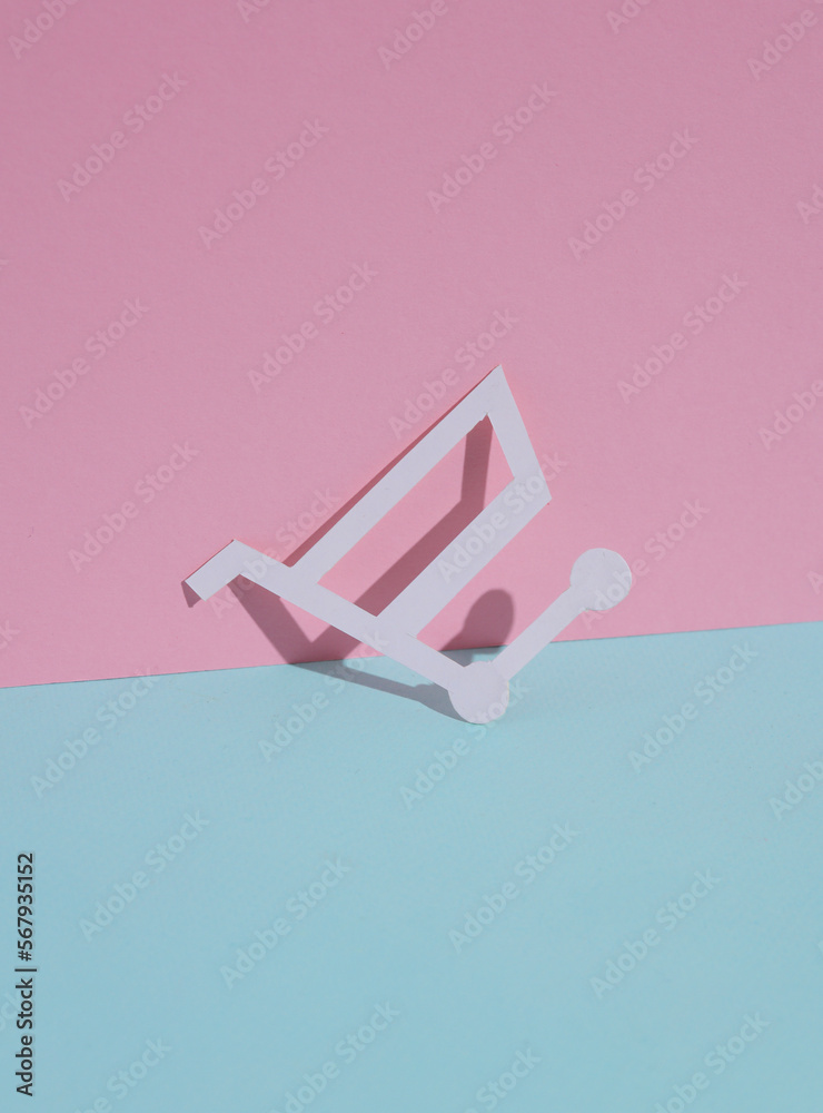 Paper-cut shopping cart on blue-pink pastel background. Creative layout