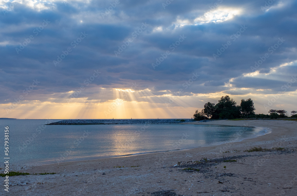 沖縄県名護市の海岸ビーチの雲と夕日の光のカーテン