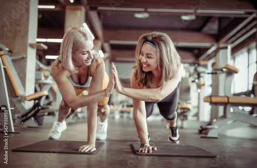 Two young athletic women friend high five, working out in the gym. Joint training. Healthy lifestyle