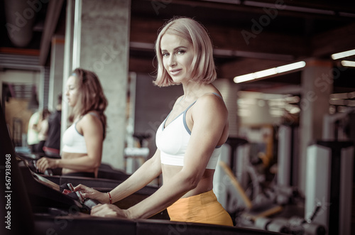 Healthy smiling young woman exercising on a treadmill in a modern gym. Health and Fitness, Cardio workout