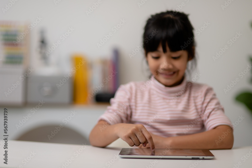 Asian little cute girl touching the digital tablet screen on the table Asian little cute girl touching the digital tablet screen on the table
