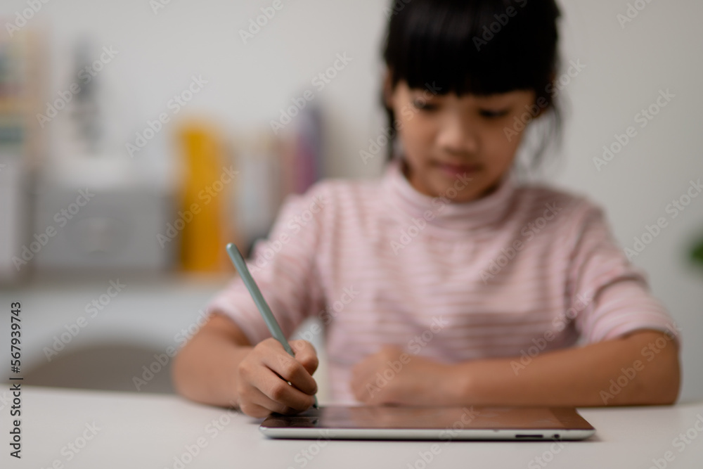 Asian little cute girl touching the digital tablet screen on the table