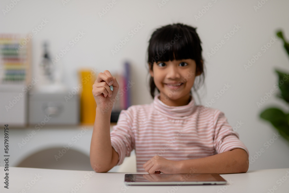 Asian little cute girl touching the digital tablet screen on the table Asian little cute girl touching the digital tablet screen on the table