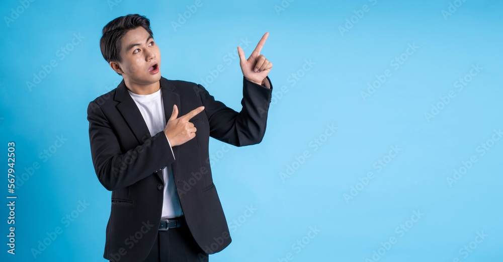 Young business man wearing a vest posing on a blue background Young business man wearing a vest posing on a blue background