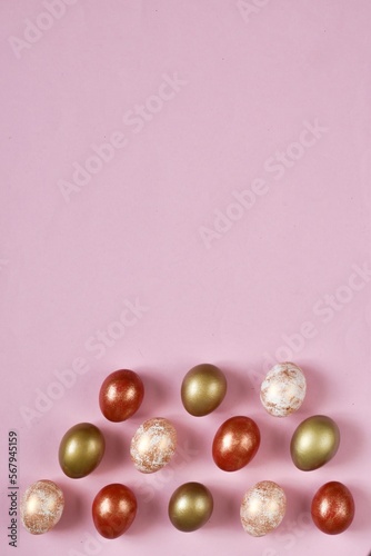 Colorful Easter Eggs bottom border over a pastel pink background. Vertical banner with Copy space. Flat lay composition