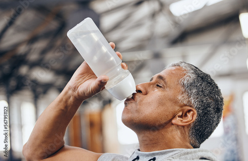 Man, fitness and drinking water bottle for hydration after workout, exercise or cardio training indoors. Sporty male staying hydrated for healthy endurance, recovery or thirst from sports exercising photo