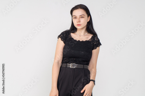 A pretty young brunette girl poses standing on a white background / An office employee is dressed in a black business suit around her a lot © Михаил Таратонов