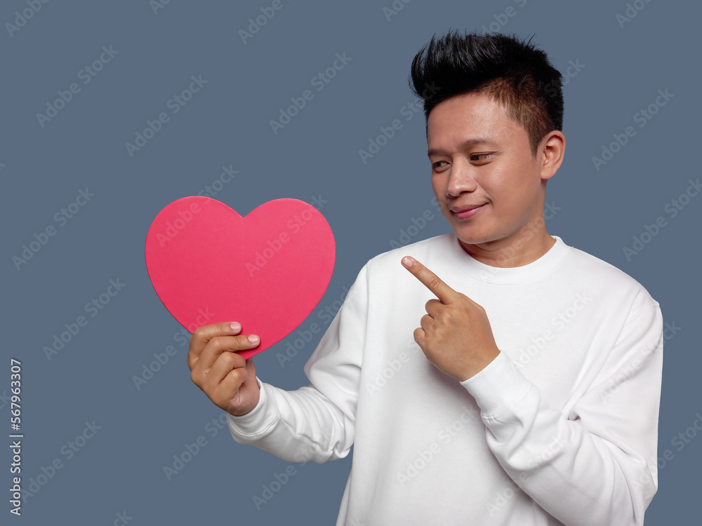 Man holding and pointing red heart shape isolated on plain background. Man holding and pointing red heart shape isolated on plain background.