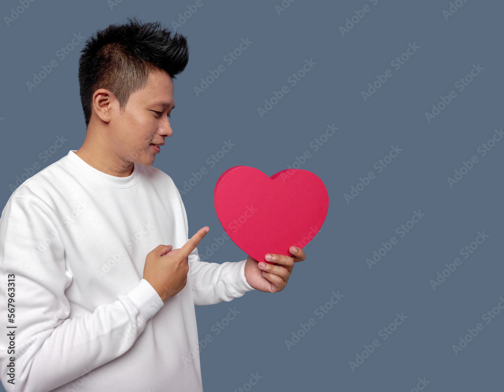 Man holding and pointing red heart shape isolated on plain background Man holding and pointing red heart shape isolated on plain background