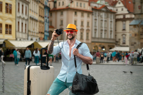 Tourist walking on city street. Man traveller with sunglasses, hat and camera. Man with travel bag ready to travel on his vacation.