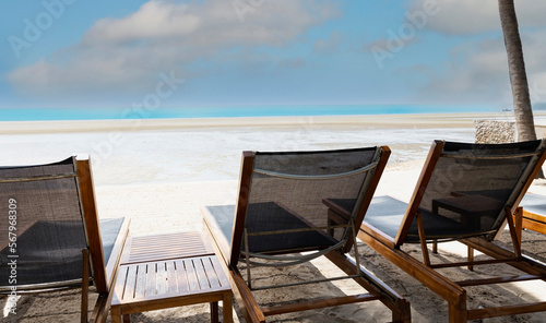 Fototapeta Naklejka Na Ścianę i Meble -  Empty folding chair on shore at beach against blue sky background