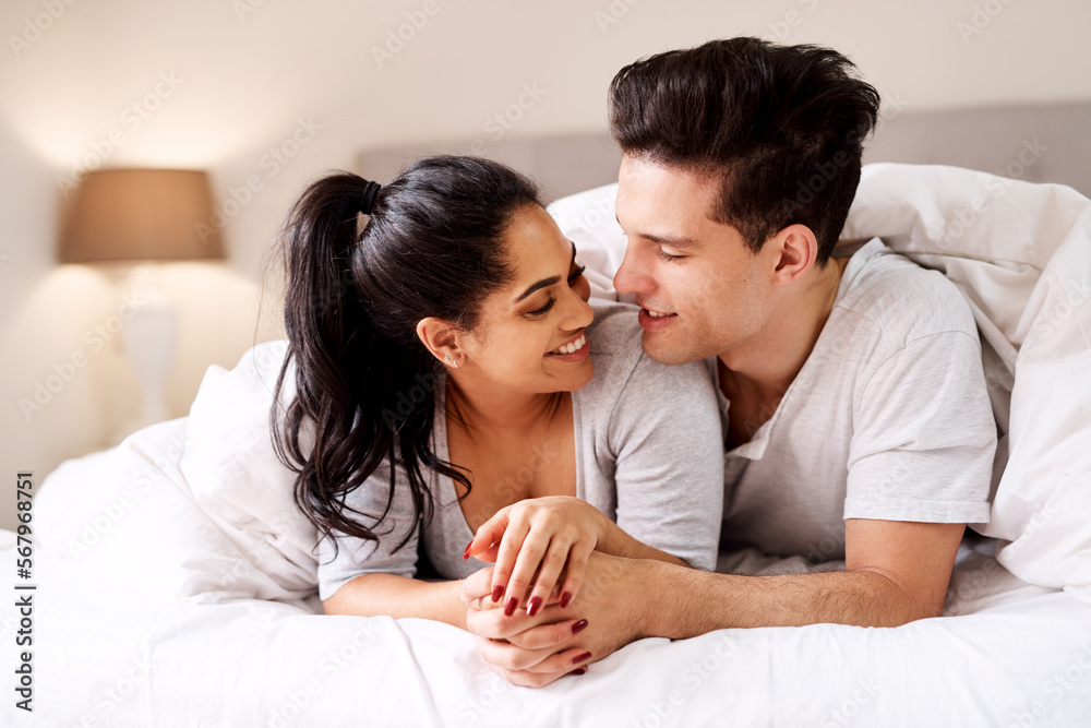 Bedroom, love and interracial couple together in home holding hands at night. Smile diversity and marriage of an Indian woman and man with love, care and relax happiness with a smile in a house Bedroom, love and interracial couple together in home holding hands at night. Smile diversity and marriage of an Indian woman and man with love, care and relax happiness with a smile in a house