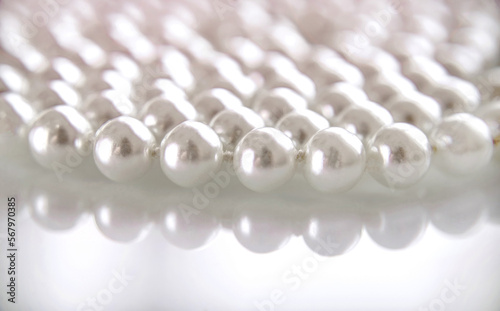 A necklace of pearls lying on white glass 
