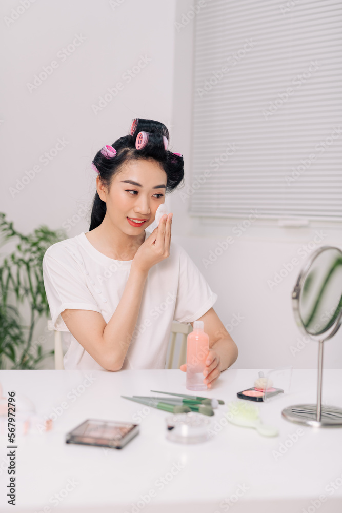 Young happy woman removing makeup from her face enjoying her skin and smiling at the mirror Young happy woman removing makeup from her face enjoying her skin and smiling at the mirror
