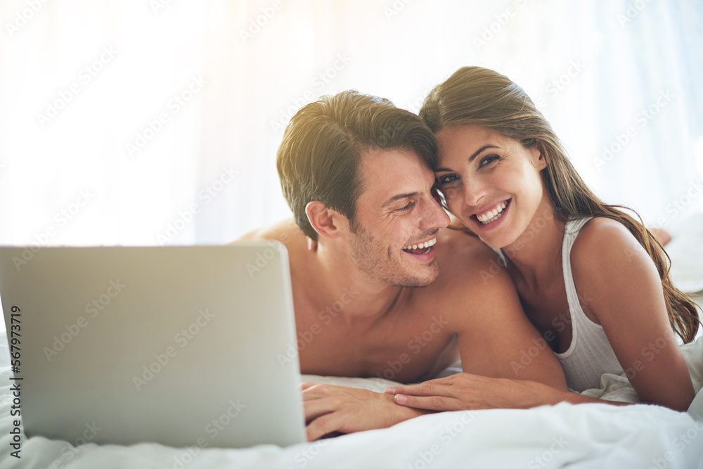 Laptop, happy and couple lying in bed together while watching a online movie or video at their home. Happiness, smile and portrait of a woman browsing the internet on computer with husband in bedroom