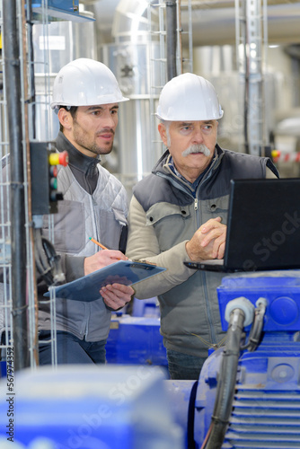 men in factory looking at paperwork
