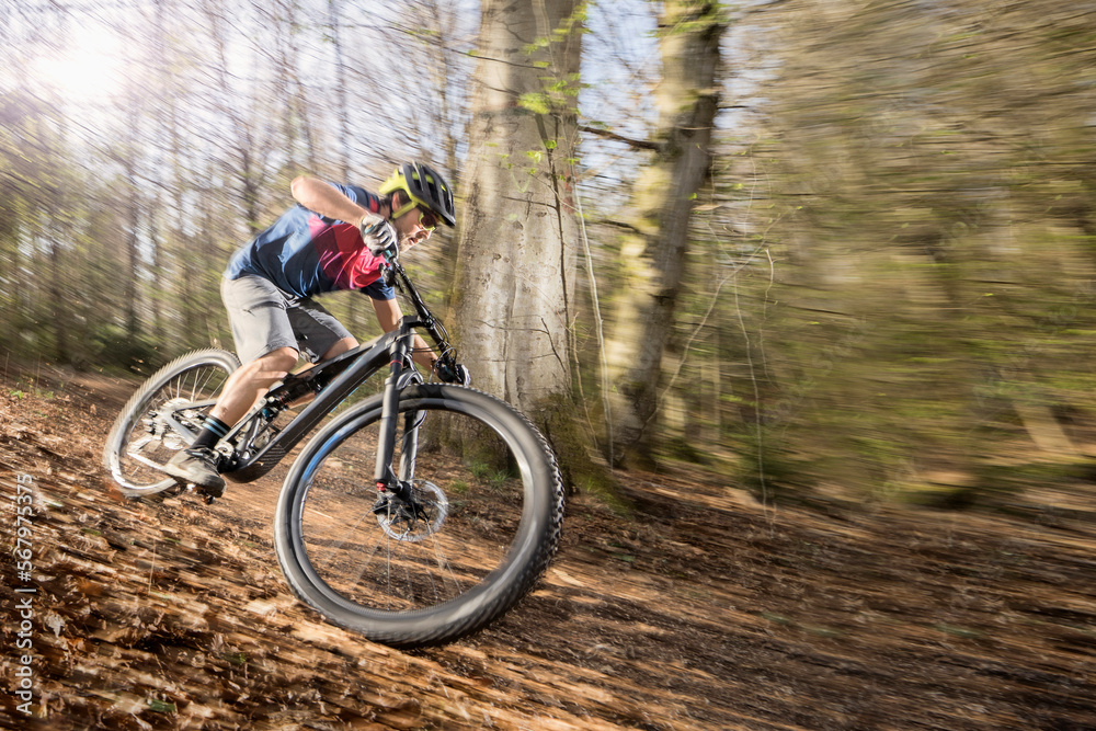 Mountain biker riding down hill on forest path, Bavaria, Germany Mountain biker riding down hill on forest path, Bavaria, Germany