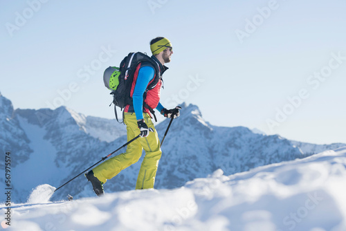 Skier climbing up on snow covered mountain photo