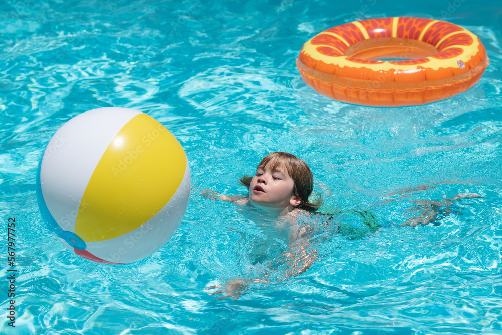 Boy kid swimming and playing in a pool. Child playing in swim pool. Summer vacation concept. Summer kids portrait.
