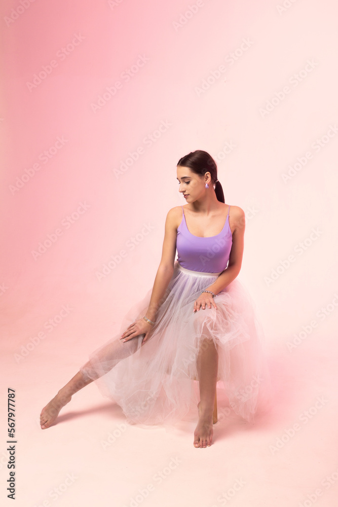 Fototapeta premium Young woman in a tulle skirt posing on a white background.