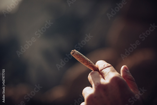 Boy smoking a marijuana joint on top of a mountain during sunset photo