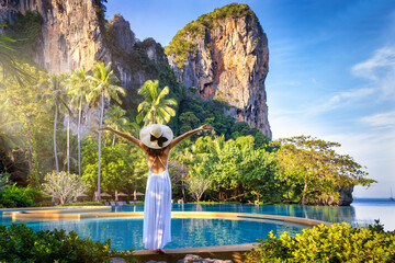 A summer travel concept with a woman in a white dress looking at the tropical paradise beach of Railay, Krabi, Thailand