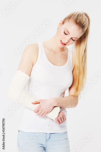 Injury, pain and woman with a broken arm after an accident isolated on a white background. Hurt, handicap and girl holding an injured and bandaged limb for an emergency in a brace on a backdrop