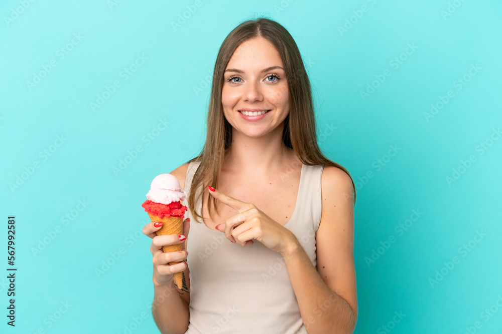 Young Lithuanian woman with cornet ice cream isolated on blue background pointing to the side to present a product Young Lithuanian woman with cornet ice cream isolated on blue background pointing to the side to present a product
