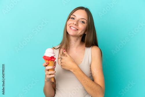 Young Lithuanian woman with cornet ice cream isolated on blue background giving a thumbs up gesture