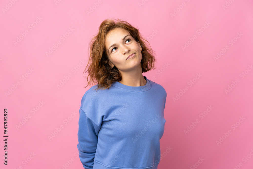 Young Georgian woman isolated on pink background and looking up Young Georgian woman isolated on pink background and looking up