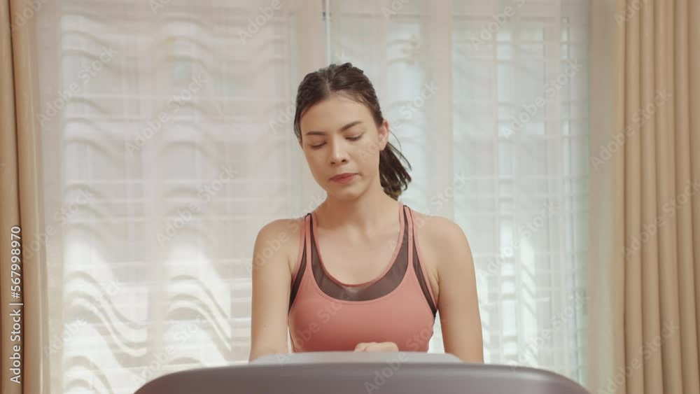 Attractive woman running on a treadmill at home decelerating on exercise machine Exercise indoors.