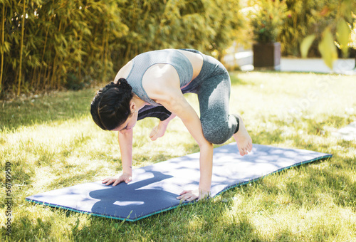 young girl doing yoga in the garden with mat