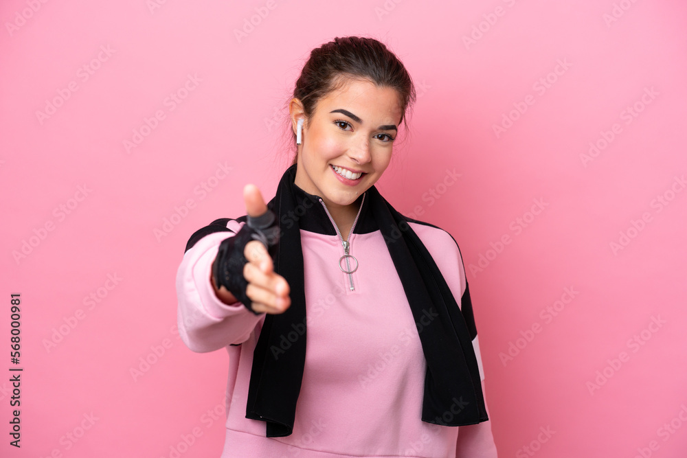 Young sport Brazilian woman isolated on pink background shaking hands for closing a good deal Young sport Brazilian woman isolated on pink background shaking hands for closing a good deal