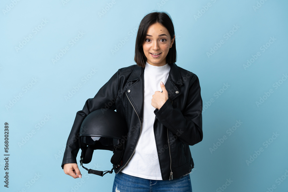 Woman holding a motorcycle helmet isolated on blue background with surprise facial expression Woman holding a motorcycle helmet isolated on blue background with surprise facial expression